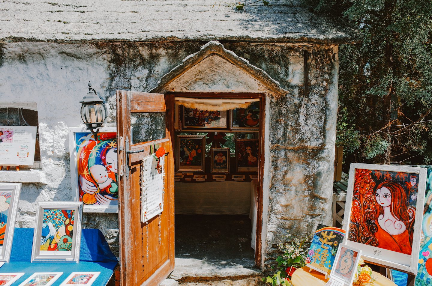 Paintings displayed on easels outside a rustic stone art gallery.